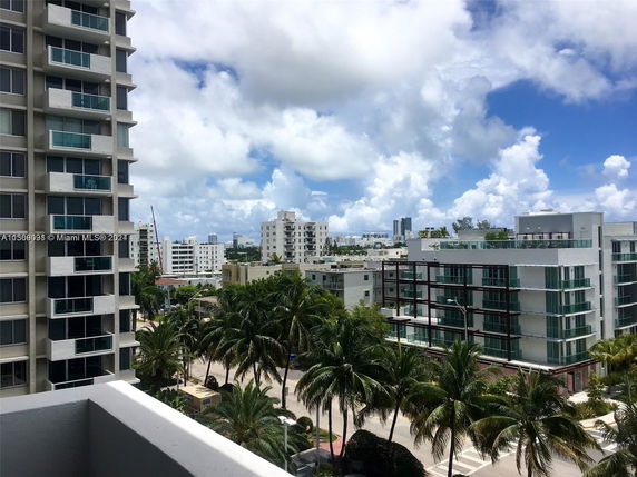 View of multiple apartment buildings and palm trees in an urban area.