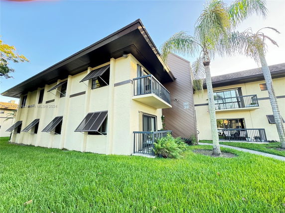 Front view of a two-story building with balconies and awning windows.