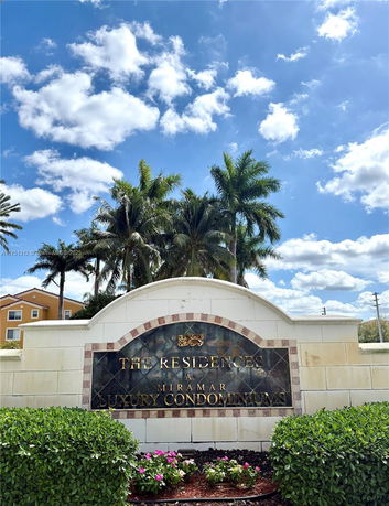Entrance sign for Miramar luxury condominiums with palm trees in the background.