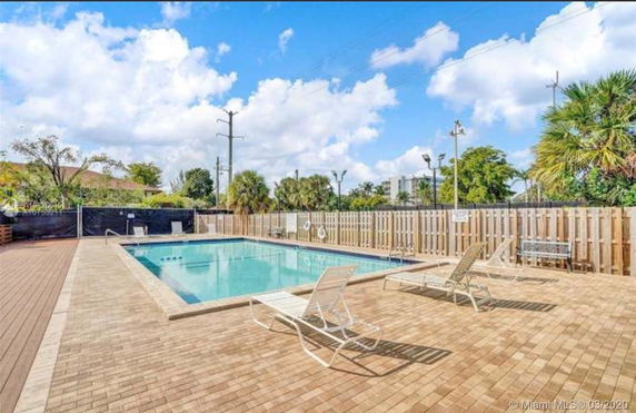 Outdoor swimming pool area with lounge chairs and a fence.