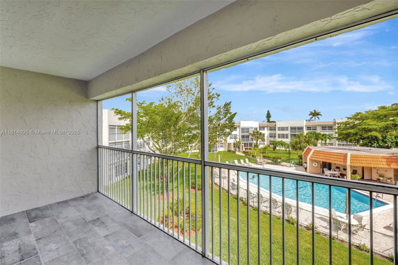 View from a balcony overlooking a swimming pool and surrounding residential buildings.