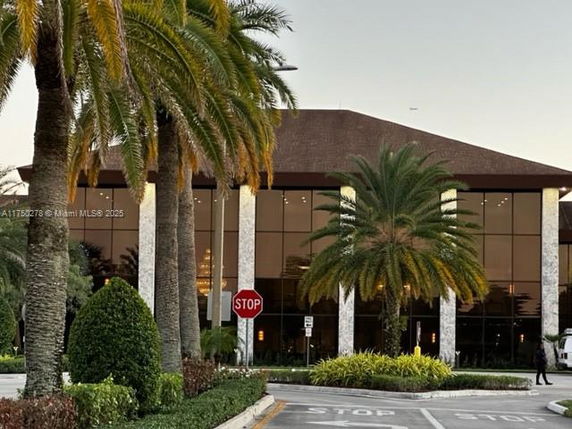 Front view of a large building with tall glass windows and palm trees in front.
