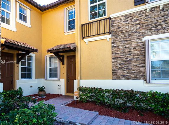 Front view of a townhouse with decorative stonework and brown shutters.