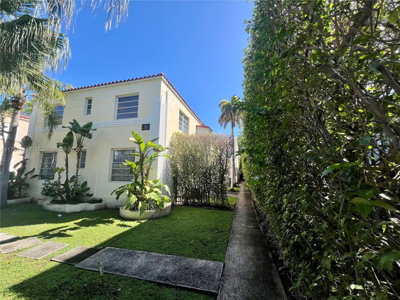 Front view of a two-story house with a red-tiled roof and surrounding vegetation.
