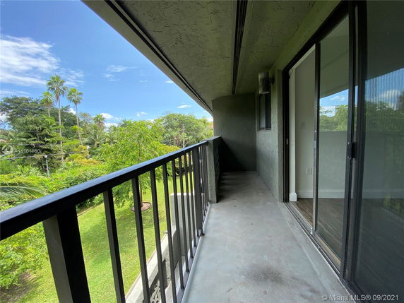 Balcony view with railing overlooking lush green surroundings and trees.