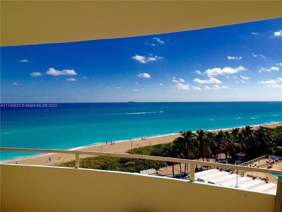 Wide-angle view of a beach and ocean from a balcony perspective.