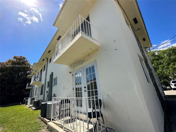 Front view of a multi-story residential building with balconies and white exterior walls.
