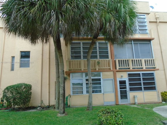 Front view of a multi-story residential building with large windows and a small balcony.