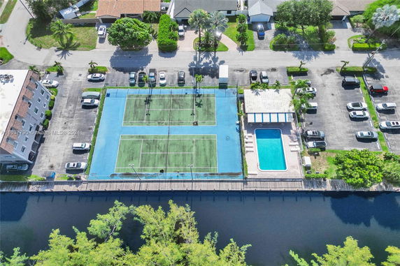 Top view of a tennis court and a swimming pool in a residential area.