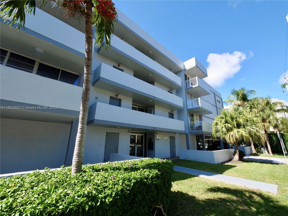 Front view of a multi-story building with balconies and palm trees.