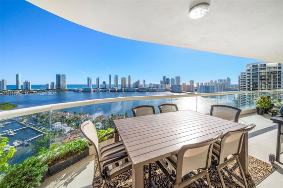 Panoramic view from a building balcony overlooking a waterfront skyline with high-rise buildings.
