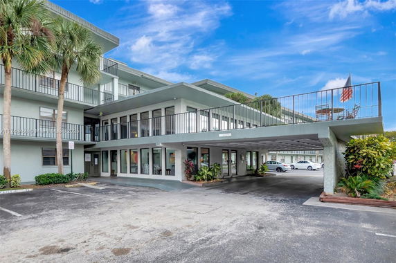Front view of a multi-story building with balconies and parking area.