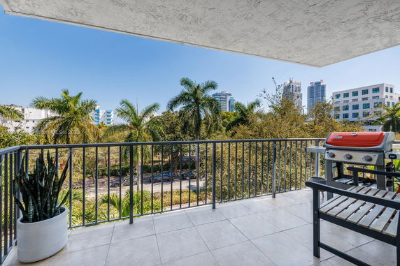 Balcony view with buildings and palm trees.