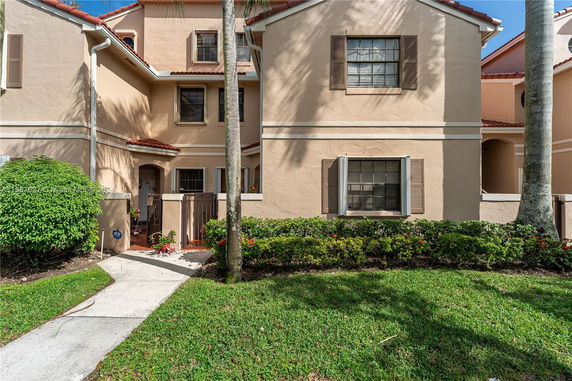 Front view of a multi-story residential building with stucco walls and brown window shutters.