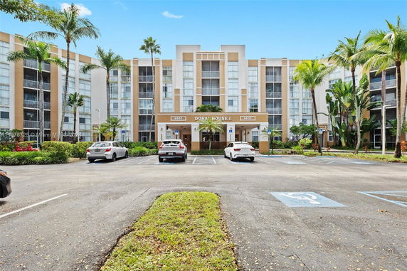 Front view of a multi-story residential building with parking area.