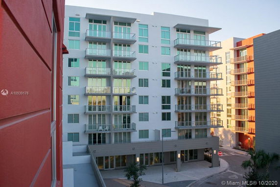 Front view of a modern multi-story apartment building with balconies and large windows.