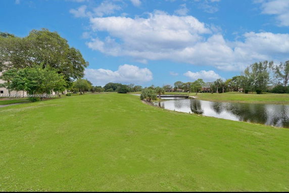 View of a grassy area with a pond and trees.
