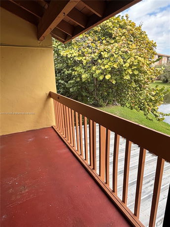 A balcony view featuring a wooden railing and nearby trees at an elevated level.