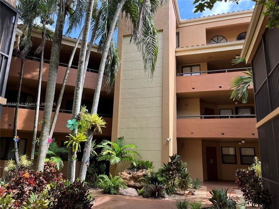 Front view of a multi-story building with balconies and palm trees.