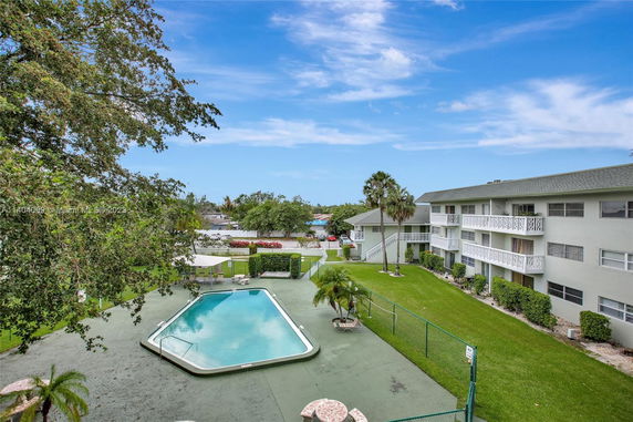Outdoor view of an apartment complex with a swimming pool and green lawn.