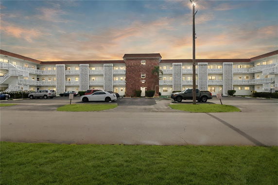Front view of a multi-story residential building with balconies and parking area.