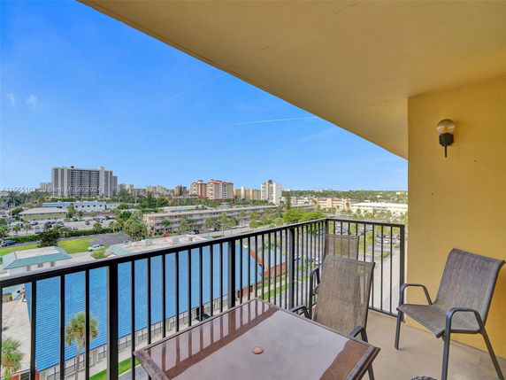 Panoramic view from a balcony overlooking a cityscape with multiple buildings.