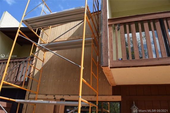 Partial view of a building under construction with scaffold and wood paneling.