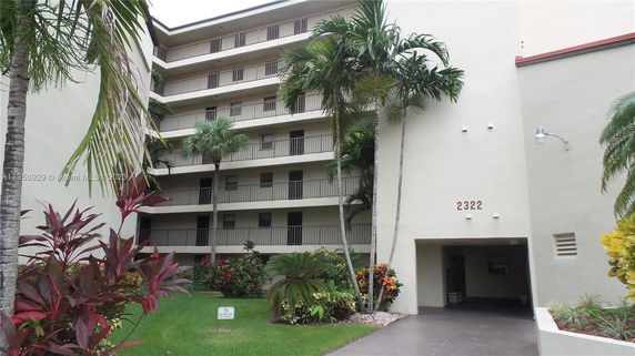 Front view of a multi-story apartment building with a covered entrance.