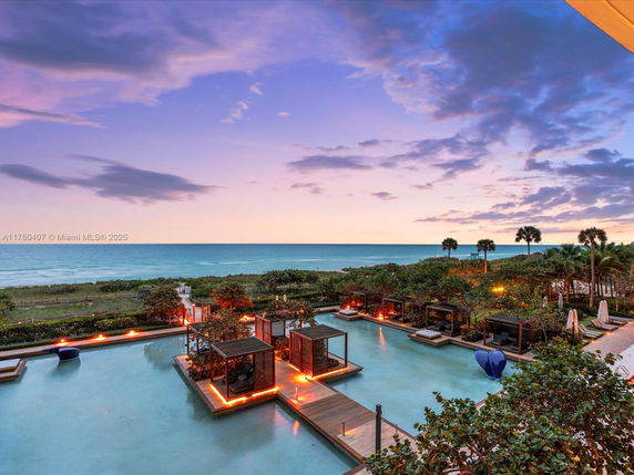 Outdoor view of a swimming pool area with ocean in the background.