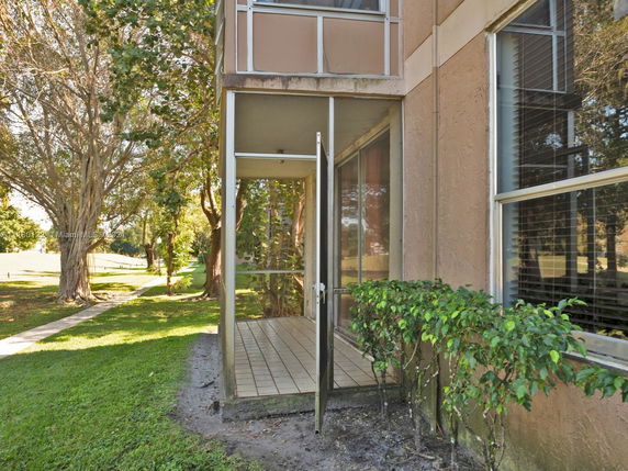View of a building corner with a glass-enclosed patio and windows.