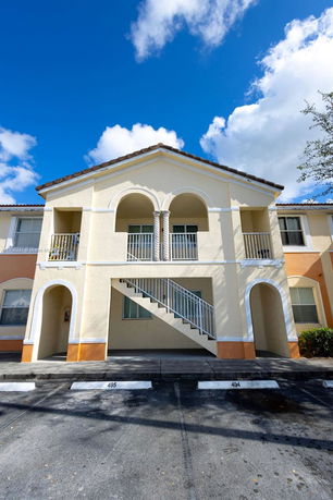 Front view of a two-story building with arches and exterior staircase.