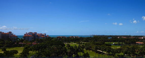 Panoramic view of a coastal area with ocean, buildings, and greenery.