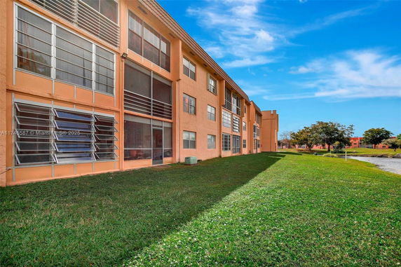 Side view of a multi-story apartment building with large windows.