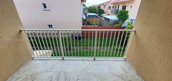 View from a balcony overlooking neighboring buildings and a backyard.