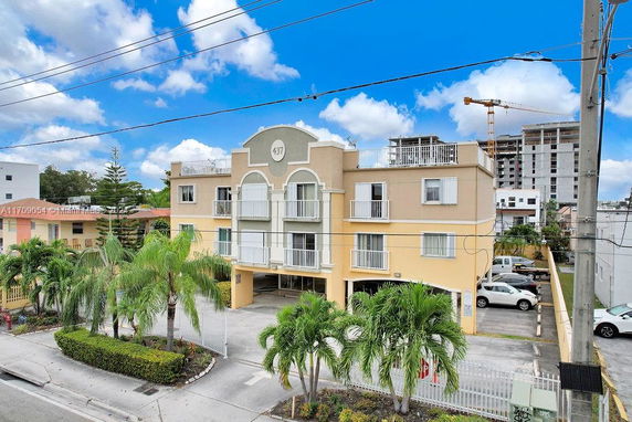 Front view of a three-story apartment building with balconies and covered parking.