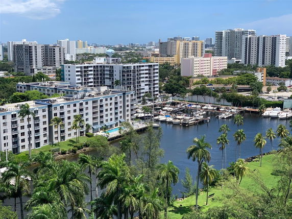 Aerial view of a waterfront urban area with multi-story buildings, a marina, and boats.