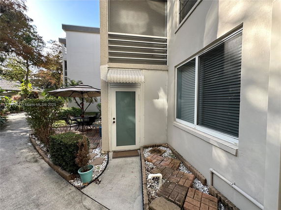 View of a building exterior with a patio area, featuring an umbrella and outdoor seating.