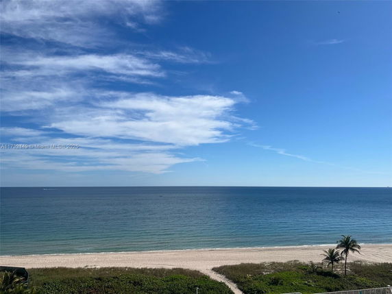 Wide angle view of a sandy beach with ocean and sky in the background.