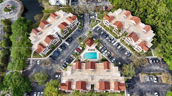 Top view of multiple residential buildings with a central swimming pool and parking lots.