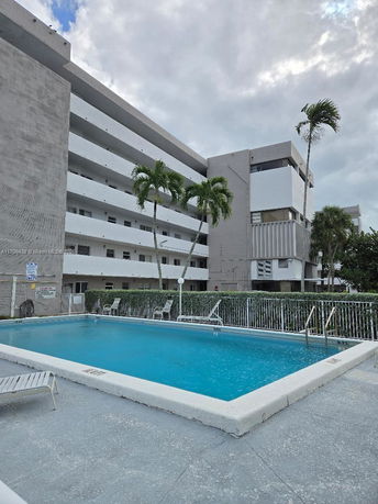 Outdoor swimming pool in front of a multi-story residential building.