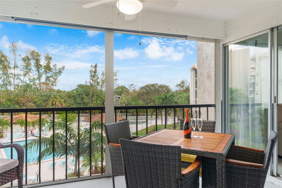View from a balcony overlooking a swimming pool and lush greenery.