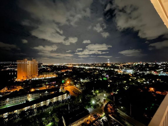 Night panoramic view of a cityscape with illuminated buildings and streetlights.