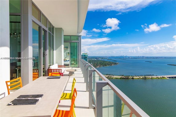 Panoramic view from a high-rise building's balcony overlooking a vast body of water and distant cityscape.