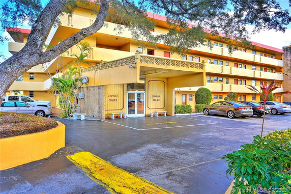 Front view of a multi-story building with balconies and parking area.