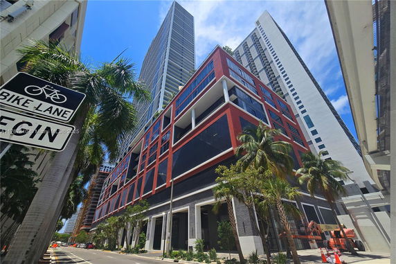 Front view of a multi-story building with a modern design featuring large windows and red accents.