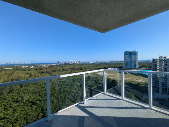 Panoramic view from a high-rise balcony showing city skyline and greenery.