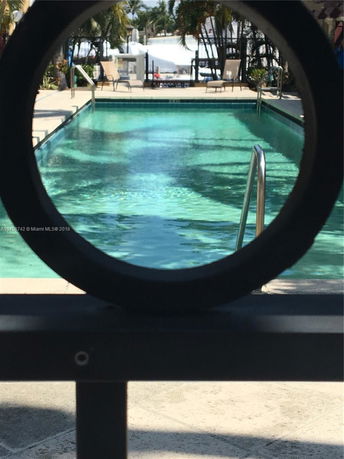 Outdoor swimming pool with lounge chairs and palm trees in the background.