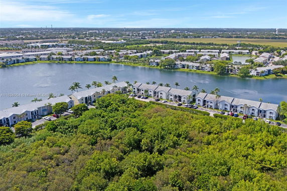 Aerial view of residential buildings along a water body surrounded by greenery.