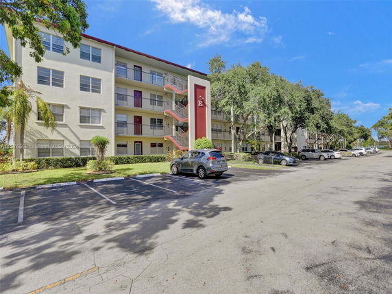 Front view of a multi-story residential building with parking area.