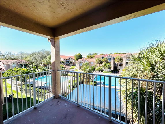 View from a balcony overlooking residential buildings and a swimming pool.